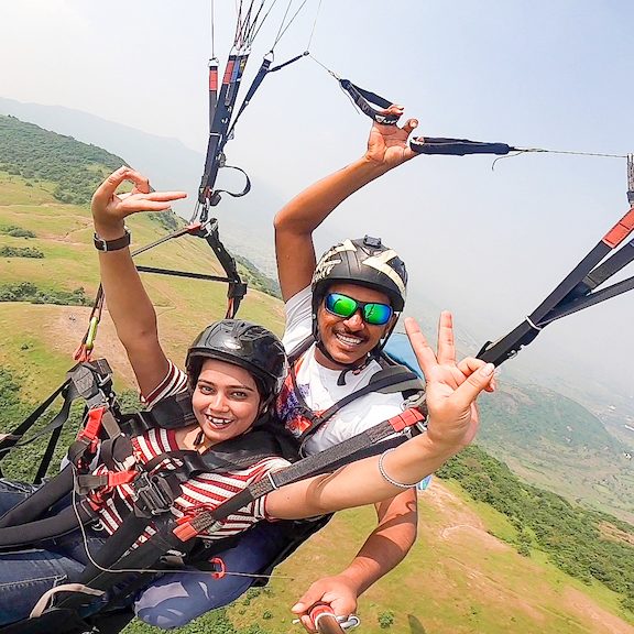 Passengers enjoying the breathtaking views while paragliding over Kamshet with their instructor.